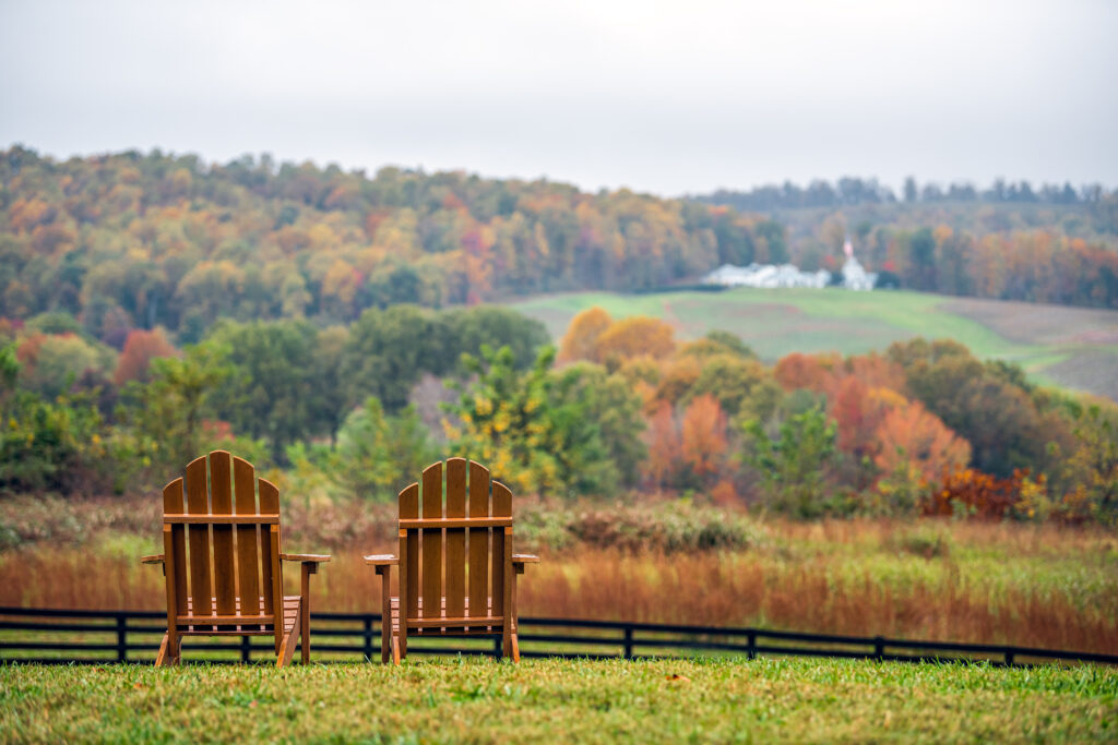 two empty adirondack chairs overlooking pasture in western nc